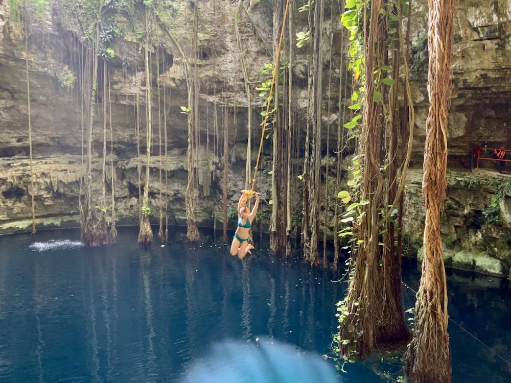 Swinging from rope swing into cenote Yucatan