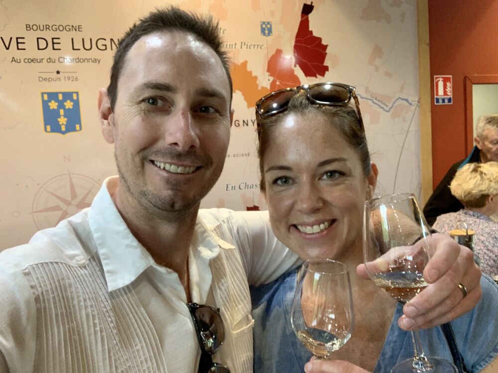 White couple at a wine tasting smile at the camera.