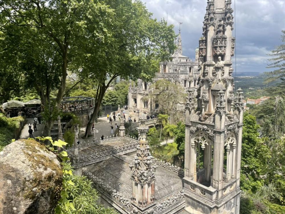 gothic architecture of Quinta de Regaleira in Sintra, Portugal. Surrounded by leafy trees.