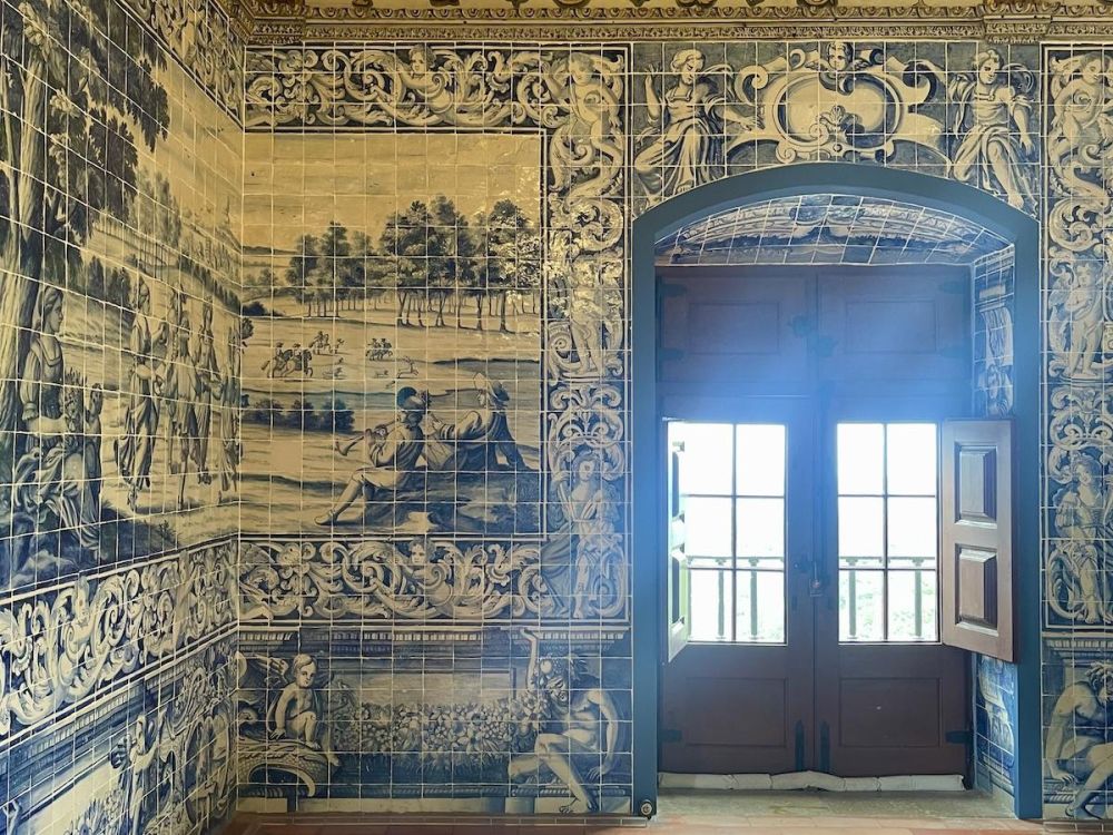 Wall to wall, floor to ceiling blue and white tilework. A set of double french doors with open windows let in glaring light.