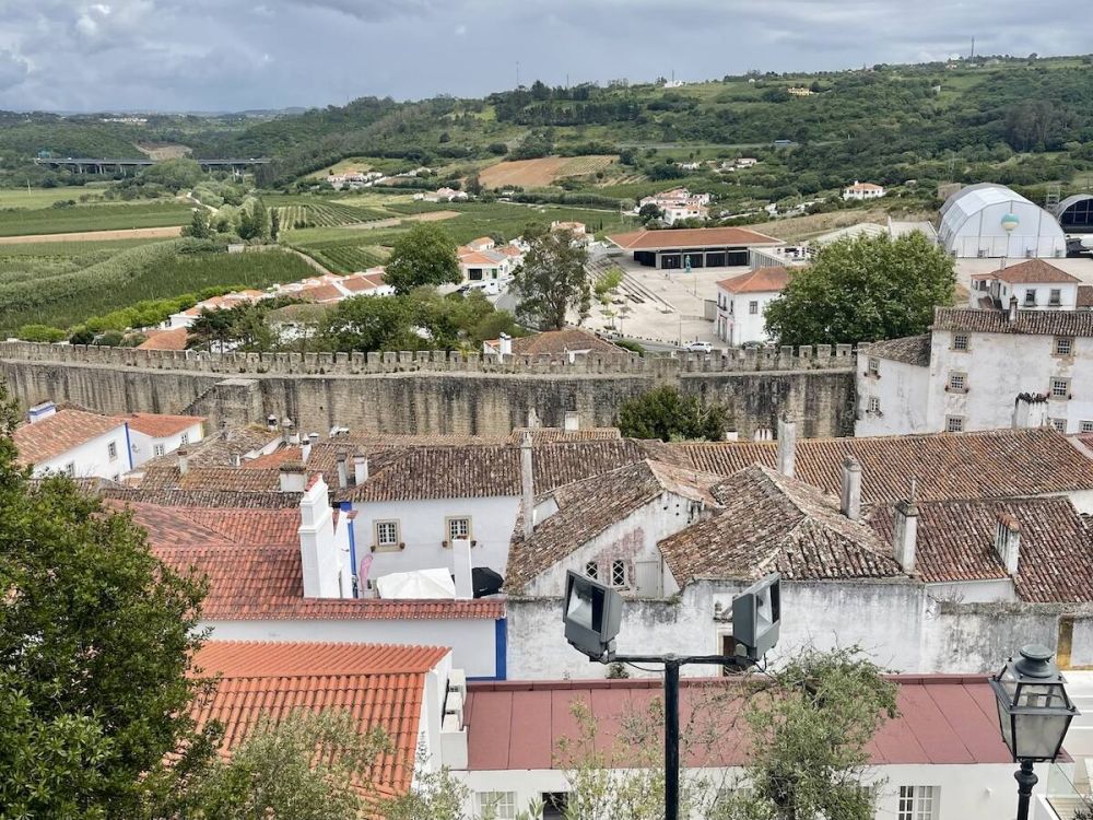 The walled city of óbidos, Portugal. Green hills stretch beyond the city walls.