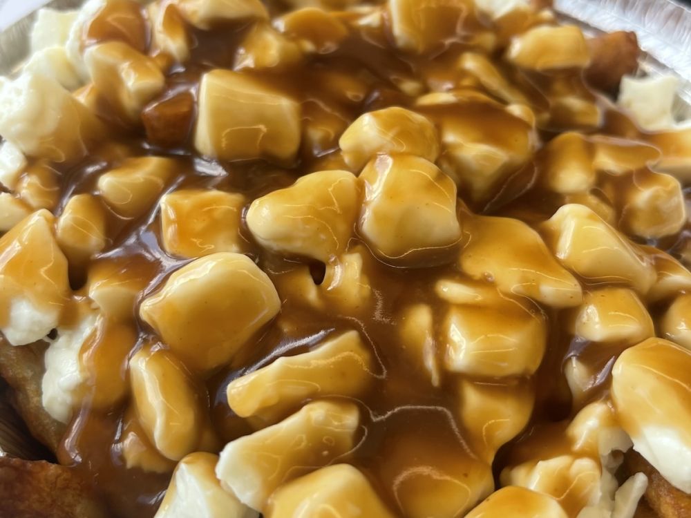 An extreme close up of gravy and cheese curds on poutine