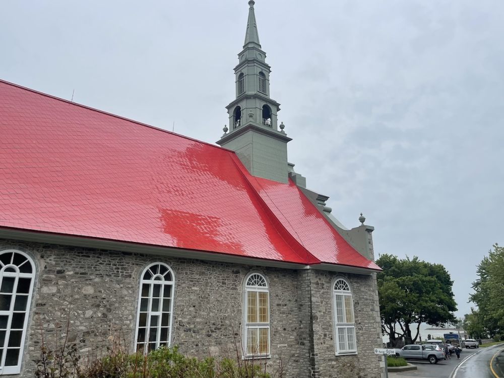 A rain-slicked red tile roof on a large stone-walled church.