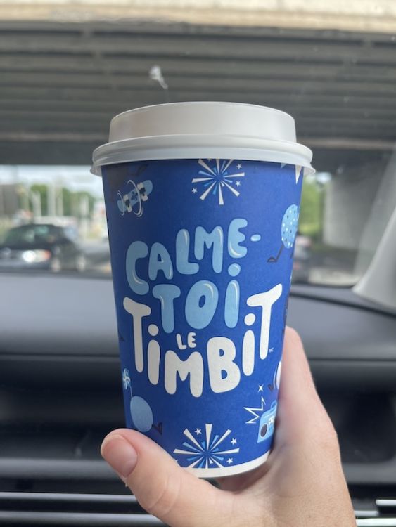 The back of a blue Tim Horton's coffee cup says calme-toi le timbit.