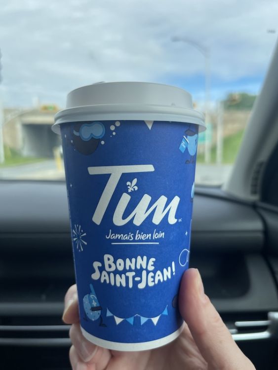 The front of a blue Tim Horton's takeaway coffee cup says 'Bonne Saint-Jean'