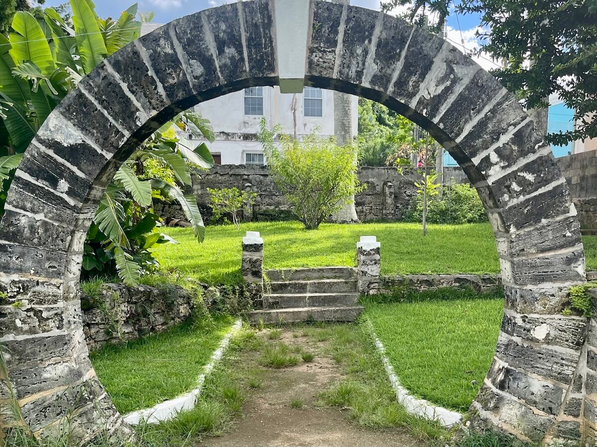 A Bermudan moongate, a circular stone archway framing a bright green garden area.